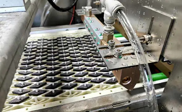 Nozzle assembly above a tray of small parts